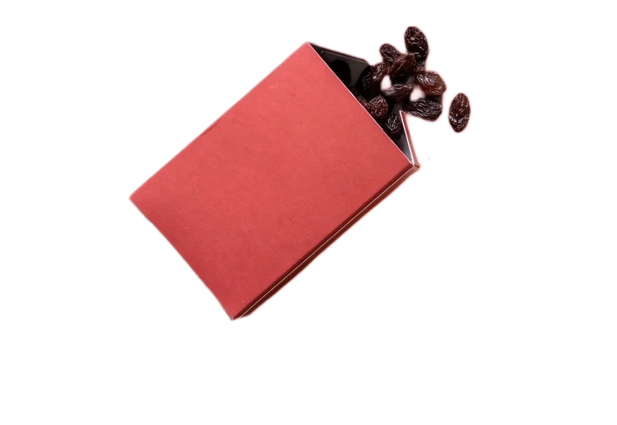 A small red box tipped over with raisins spilling out.